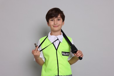 Boy pretending to be policeman on light grey background. Dreaming of future profession