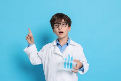 Boy with test tubes pretending to be scientist on light blue background. Dreaming of future profession