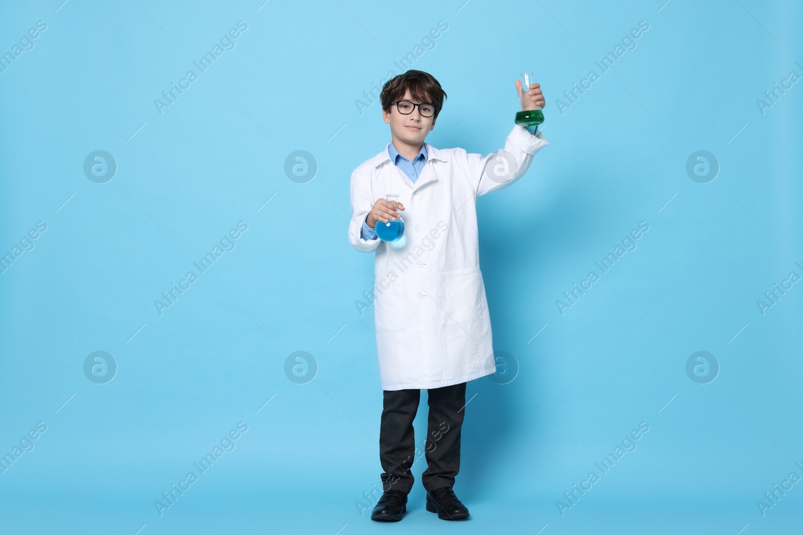 Photo of Boy with glassware pretending to be scientist on light blue background. Dreaming of future profession