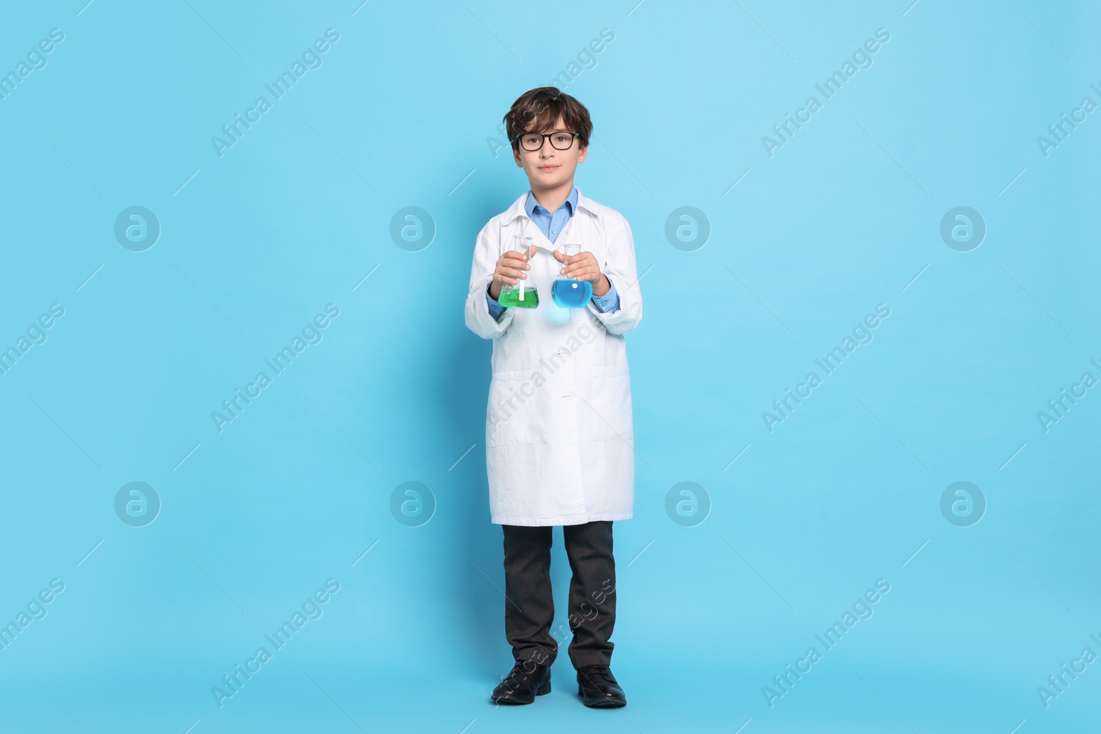 Photo of Boy with glassware pretending to be scientist on light blue background. Dreaming of future profession