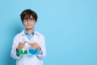 Photo of Boy with glassware pretending to be scientist on light blue background, space for text. Dreaming of future profession