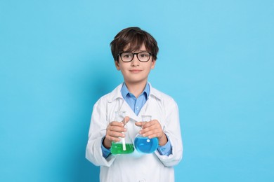 Photo of Boy with glassware pretending to be scientist on light blue background. Dreaming of future profession