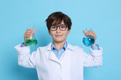 Photo of Boy with glassware pretending to be scientist on light blue background. Dreaming of future profession