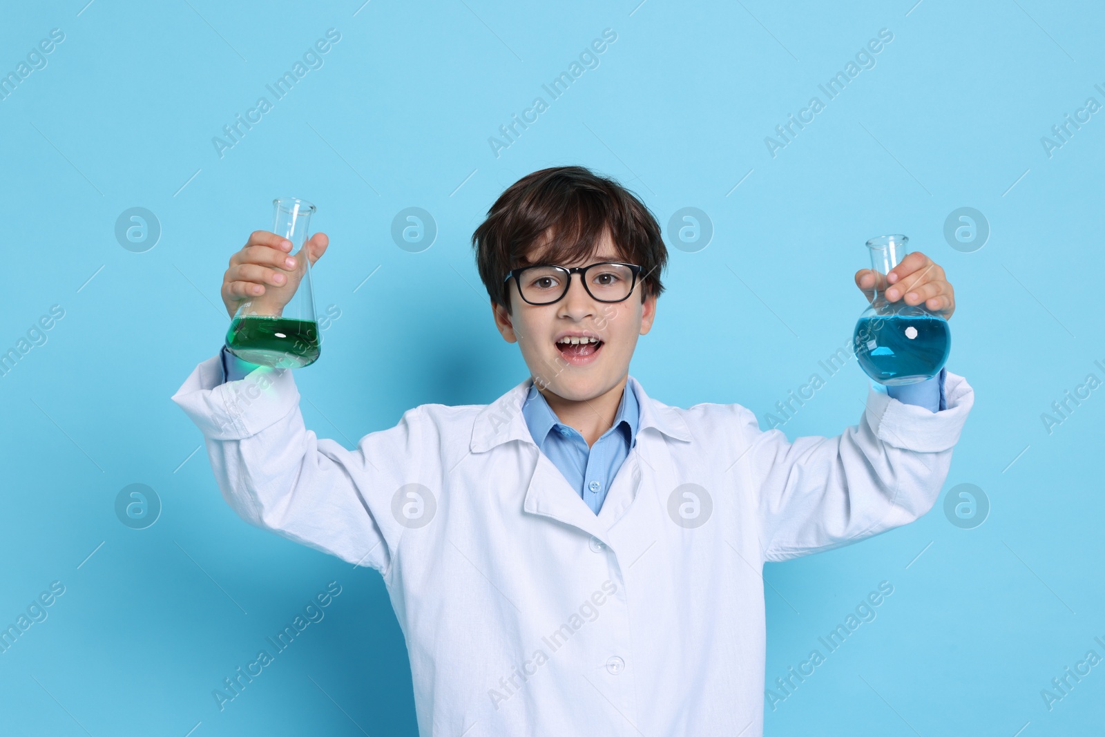 Photo of Boy with glassware pretending to be scientist on light blue background. Dreaming of future profession