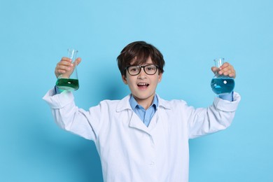 Boy with glassware pretending to be scientist on light blue background. Dreaming of future profession