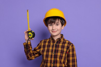 Photo of Boy with measuring tape pretending to be builder on violet background. Dreaming of future profession