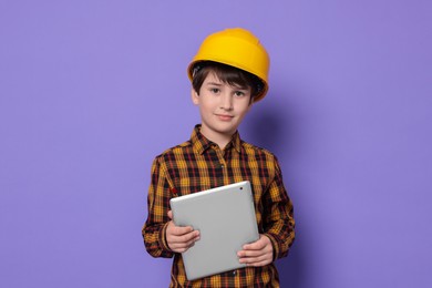 Boy with tablet pretending to be architect on violet background. Dreaming of future profession