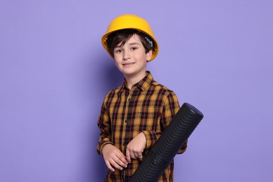 Photo of Boy with blueprint tube pretending to be architect on violet background. Dreaming of future profession