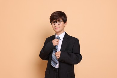 Boy in suit pretending to be businessman on beige background. Dreaming of future profession