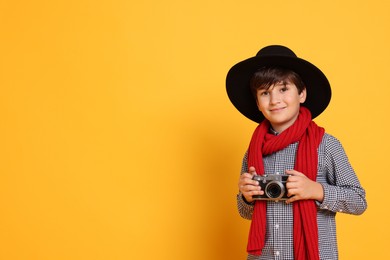 Boy with camera pretending to be photographer on orange background, space for text. Dreaming of future profession