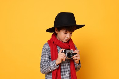 Photo of Boy with camera pretending to be photographer on orange background. Dreaming of future profession