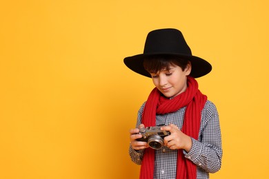 Boy with camera pretending to be photographer on orange background, space for text. Dreaming of future profession