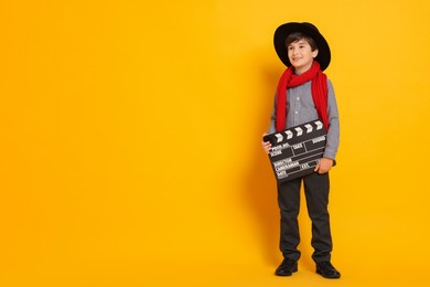 Boy with clapper pretending to be movie director on orange background, space for text. Dreaming of future profession