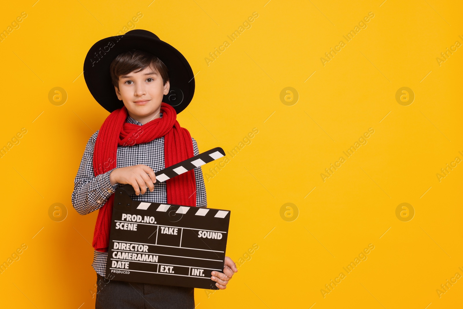 Photo of Boy with clapper pretending to be movie director on orange background, space for text. Dreaming of future profession