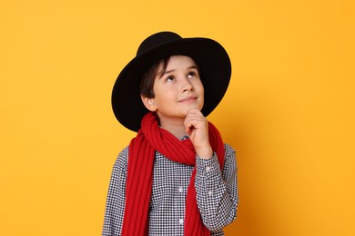 Photo of Boy with hat and scarf on orange background. Dreaming of future profession