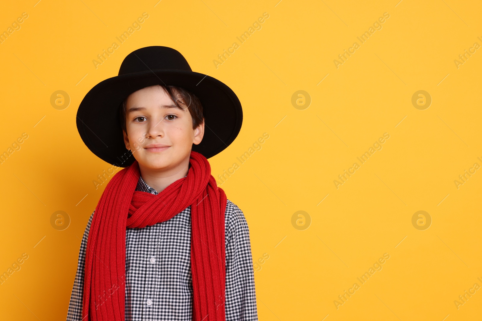 Photo of Boy with hat and scarf on orange background, space for text. Dreaming of future profession