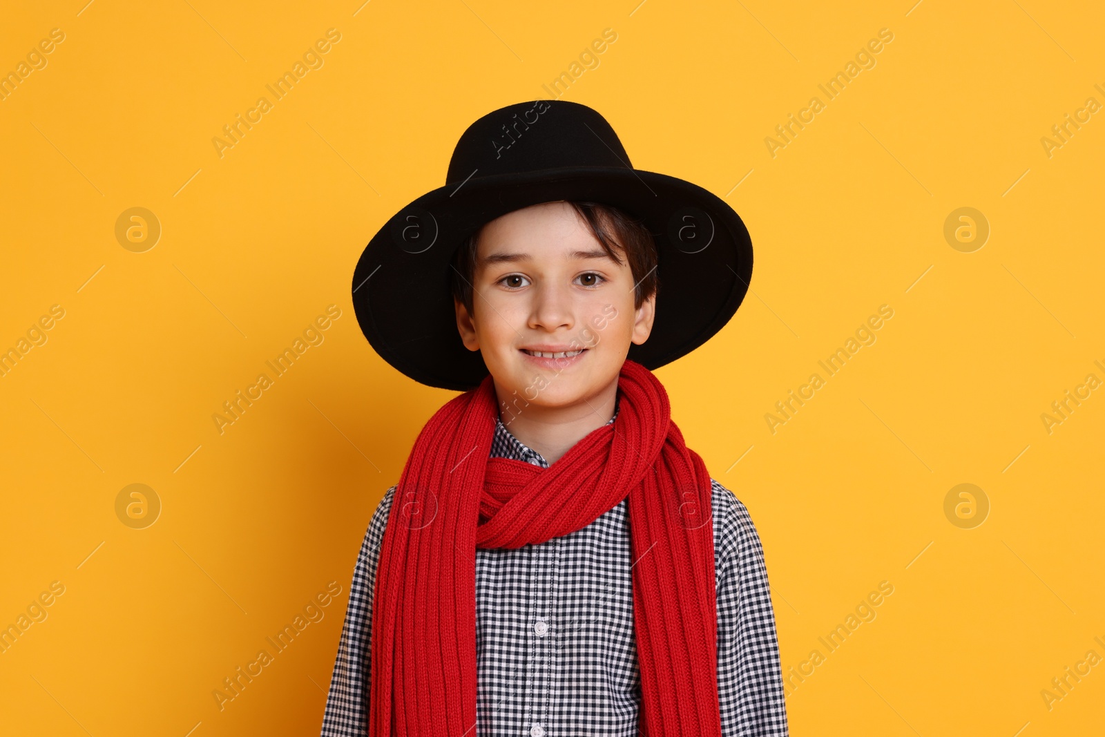 Photo of Boy with hat and scarf on orange background. Dreaming of future profession