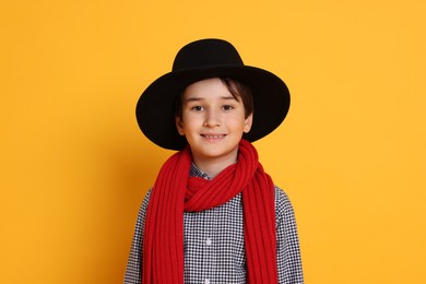 Boy with hat and scarf on orange background. Dreaming of future profession