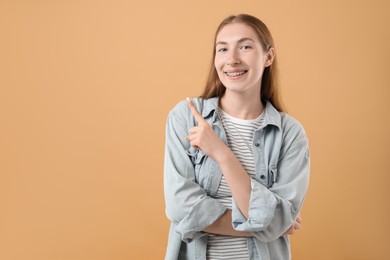 Photo of Smiling girl with braces on beige background, space for text