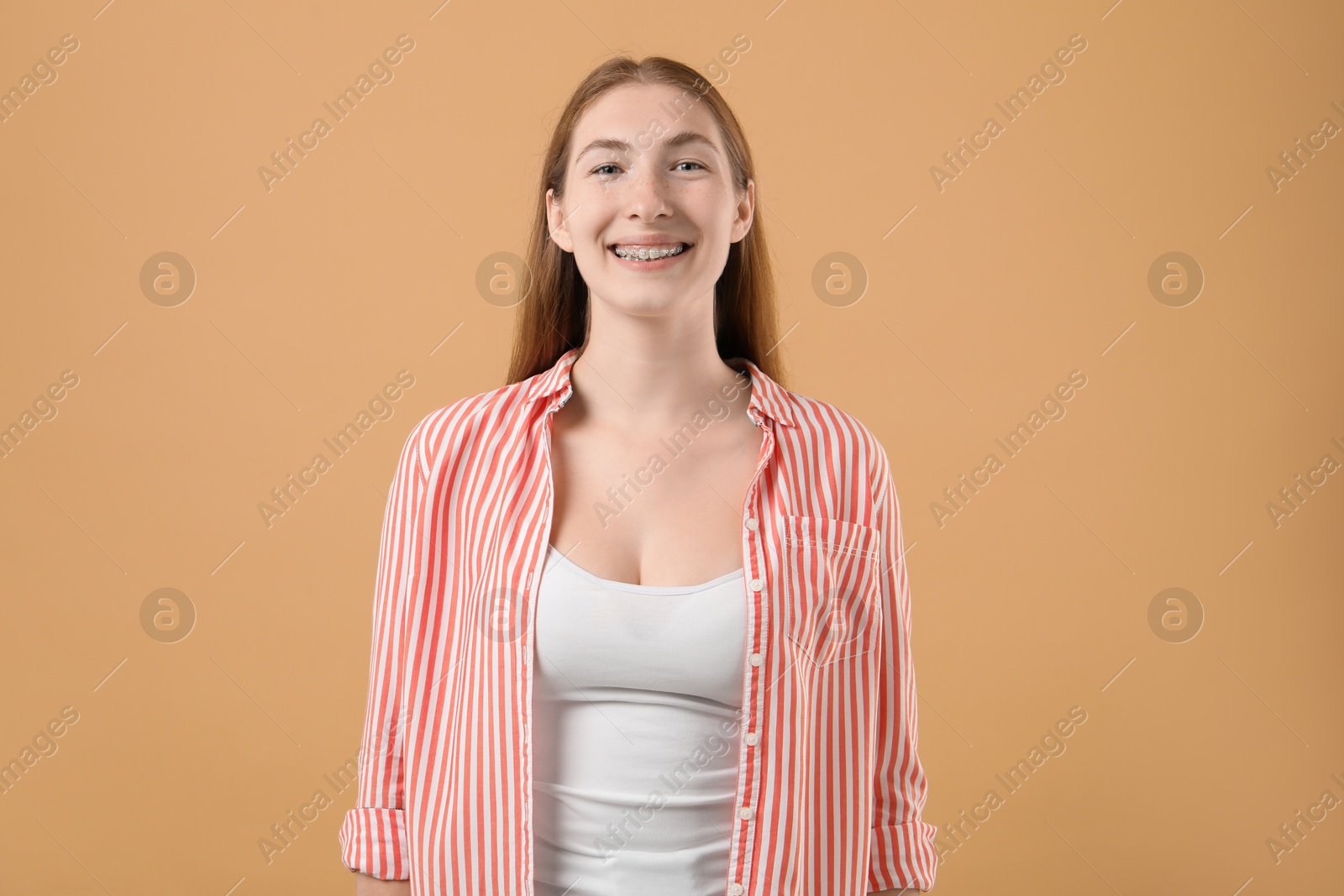 Photo of Smiling girl with braces on beige background