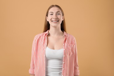 Photo of Smiling girl with braces on beige background