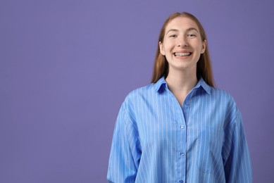 Photo of Smiling girl with braces on purple background, space for text