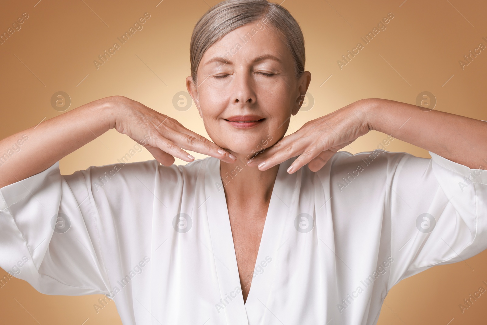 Photo of Face massage. Beautiful woman with healthy skin on beige background