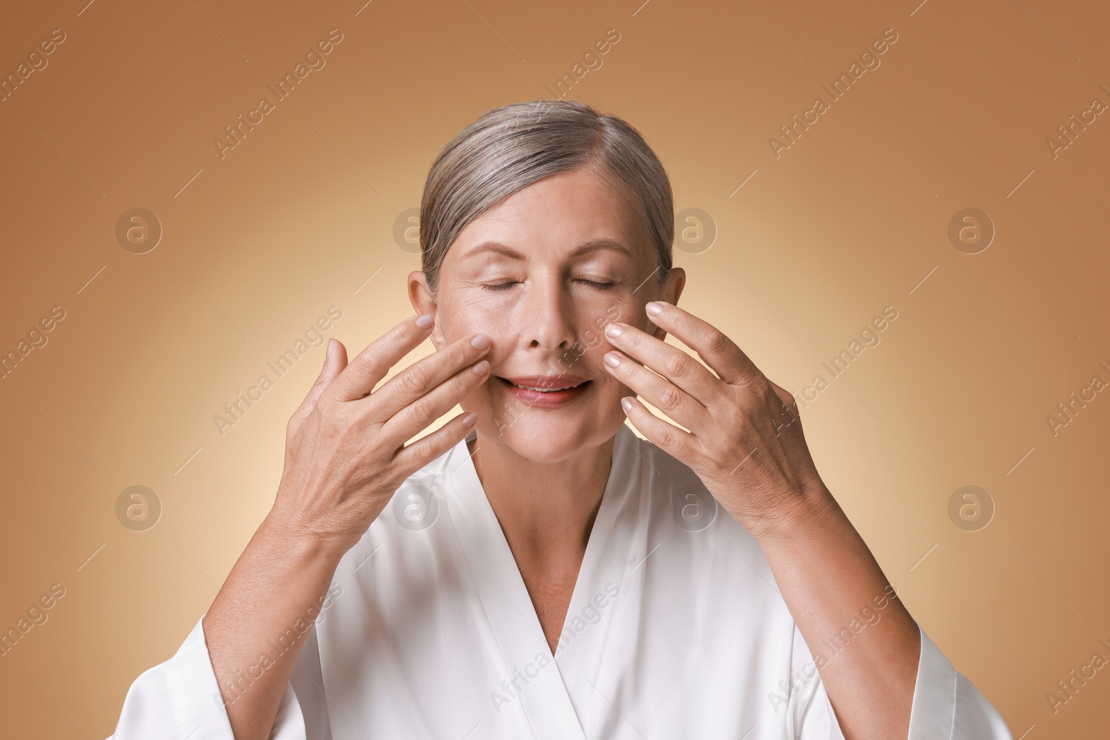 Photo of Beautiful woman doing facial massage on beige background