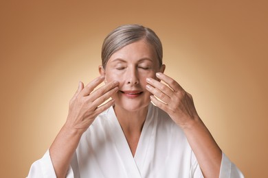 Photo of Beautiful woman doing facial massage on beige background