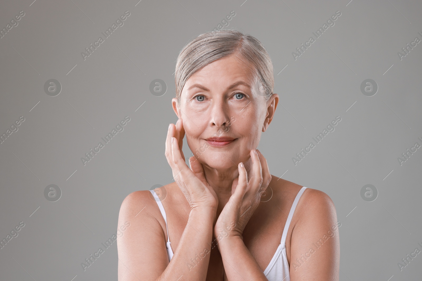 Photo of Face massage. Beautiful woman with healthy skin on grey background