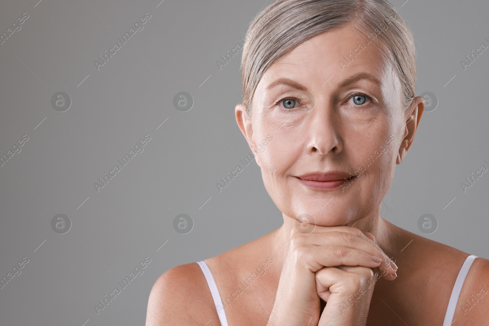 Photo of Face massage. Beautiful woman with healthy skin on grey background, space for text