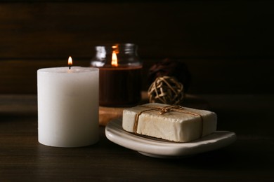 Photo of Spa composition. Burning candles and soap bar on table, closeup