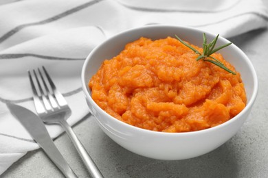 Photo of Tasty mashed sweet potato with rosemary in bowl served on grey textured table, closeup