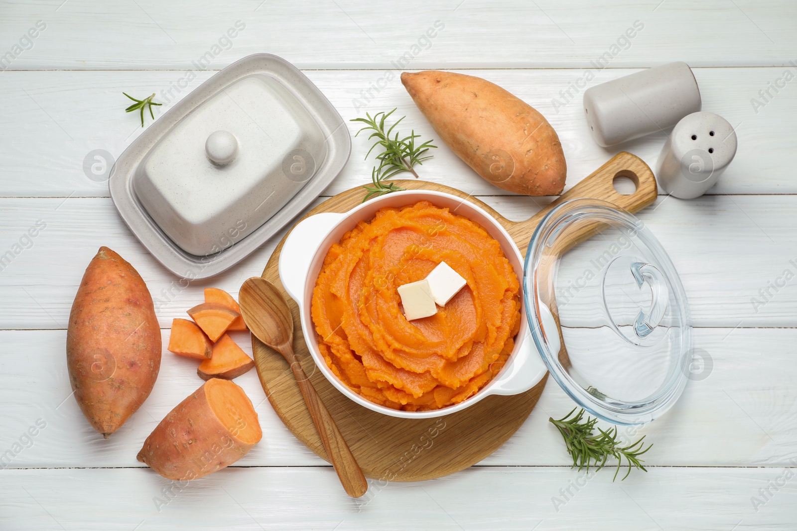 Tasty mashed sweet potato with butter in bowl, spoon, fresh vegetables and spices on white wooden table, flat lay Photo of Tasty mashed sweet potato with butter in bowl, spoon, fresh vegetables and spices on white wooden table, flat lay