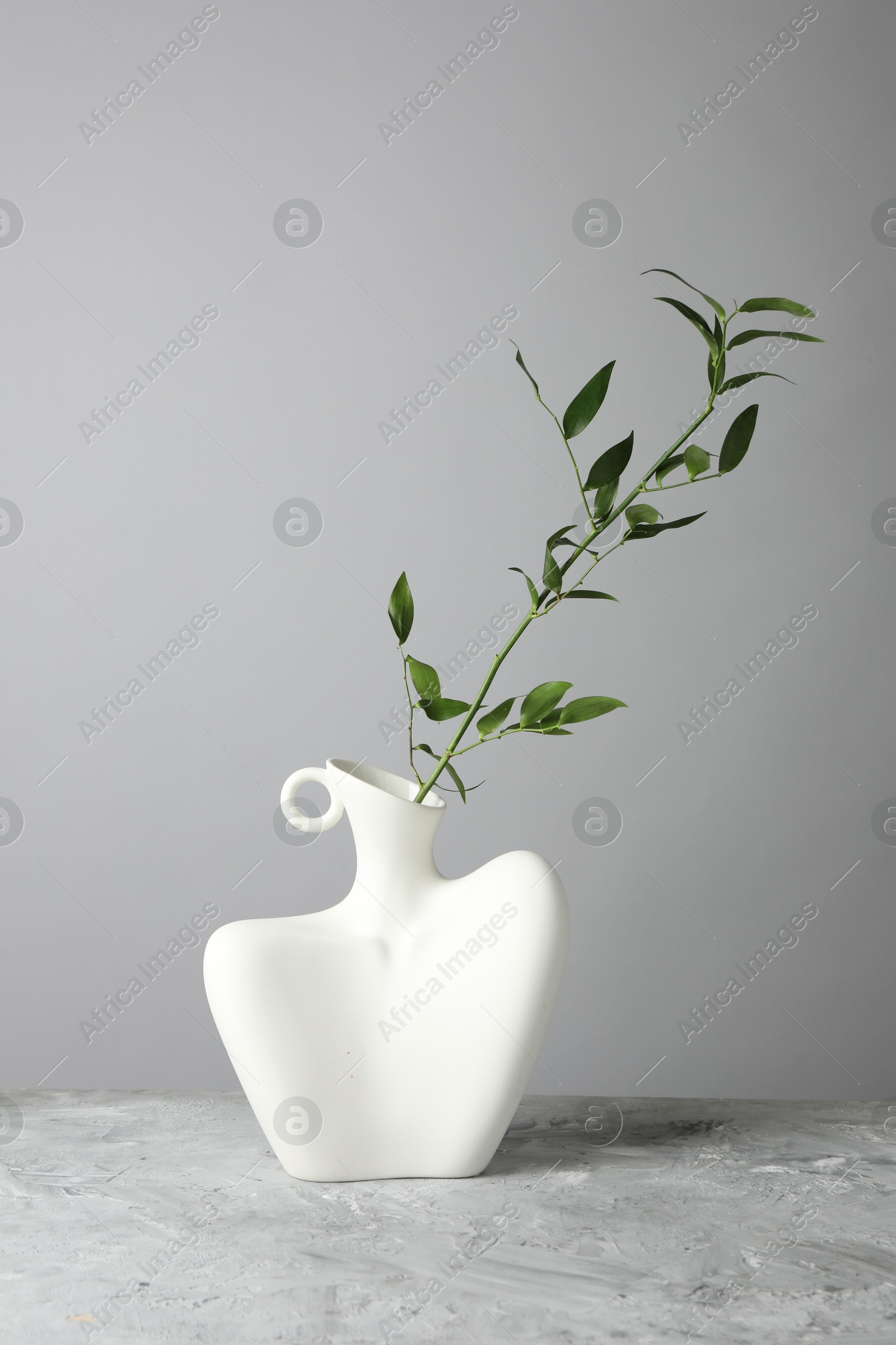 Photo of Stylish vase with green branch on grey table