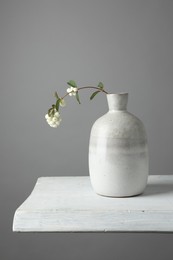 Stylish vase with snowberry branch on white table