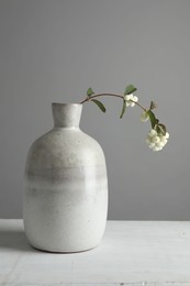 Photo of Stylish vase with snowberry branch on white table