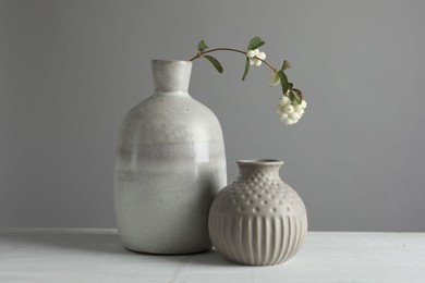 Stylish vases and snowberry branch on white table