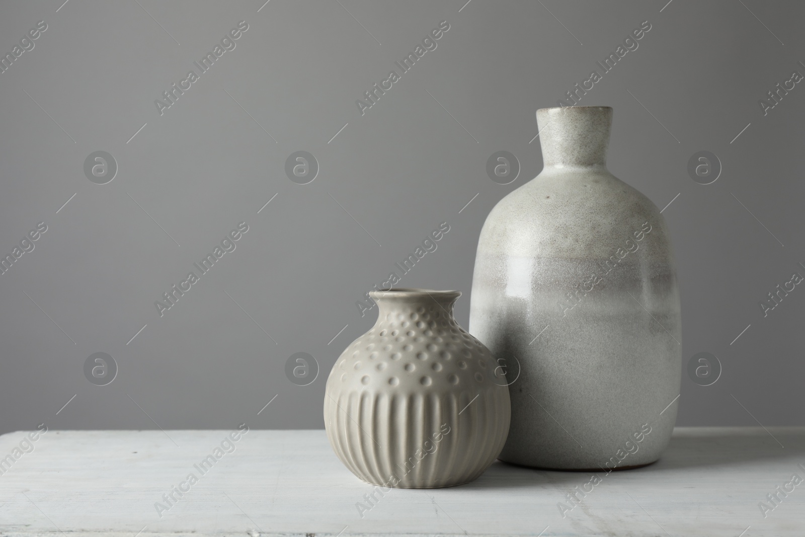 Photo of Stylish vases on white table against grey background, space for text