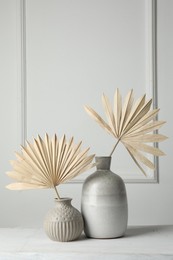 Photo of Stylish vases with dry palm leaves on white table