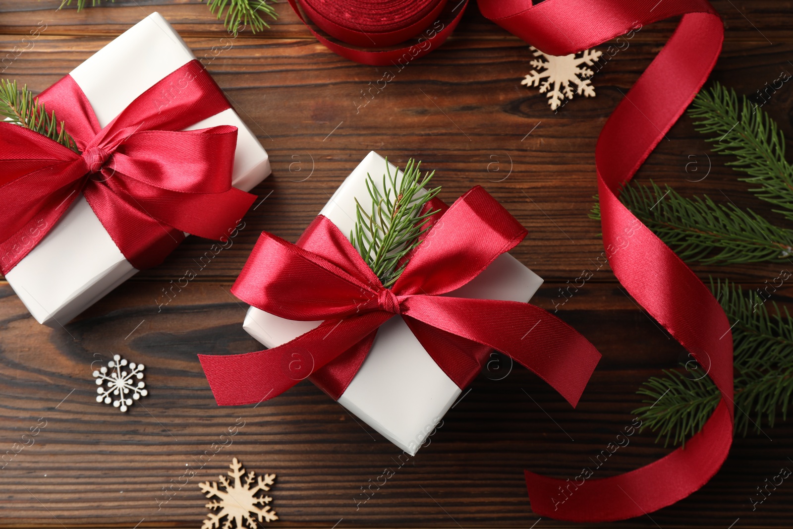 Photo of Beautiful gift boxes, ribbon and Christmas decor on wooden table, flat lay