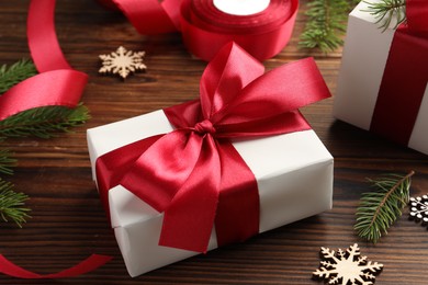 Beautiful gift boxes, ribbon and Christmas decor on wooden table, closeup