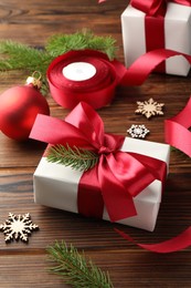 Photo of Beautiful gift boxes, ribbon and Christmas decor on wooden table