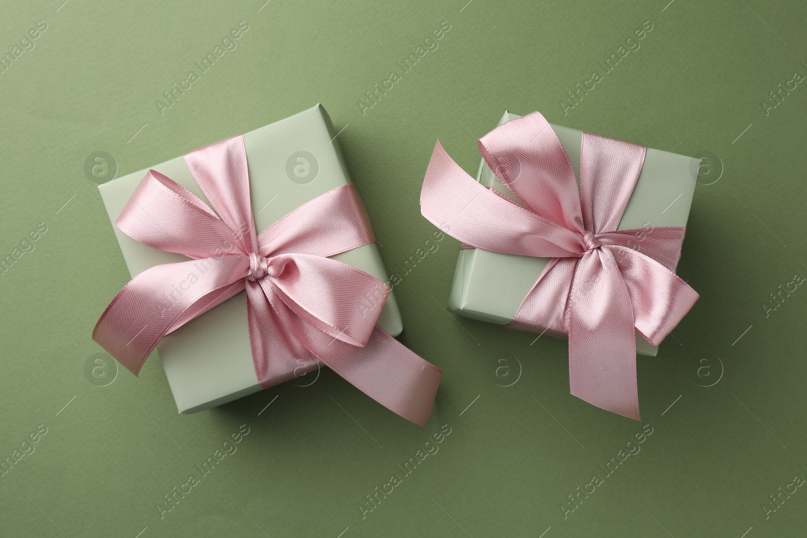 Photo of Gift boxes with pink bows on green background, top view