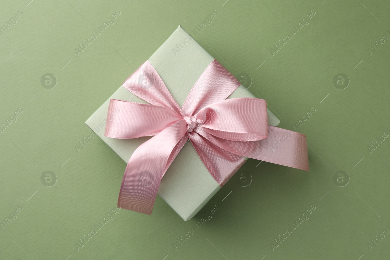 Photo of Gift box with pink bow on green background, top view