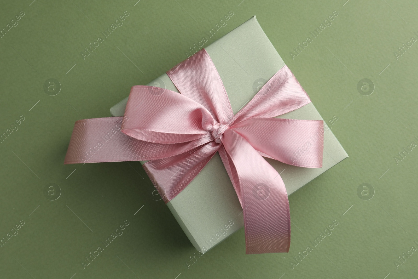 Photo of Gift box with pink bow on green background, top view