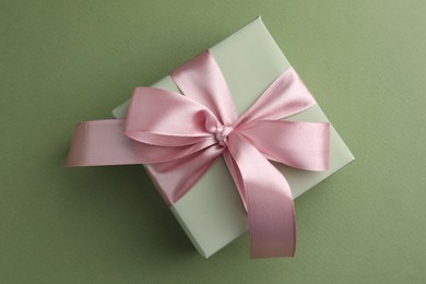 Photo of Gift box with pink bow on green background, top view