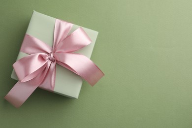 Photo of Gift box with pink bow on green background, top view. Space for text