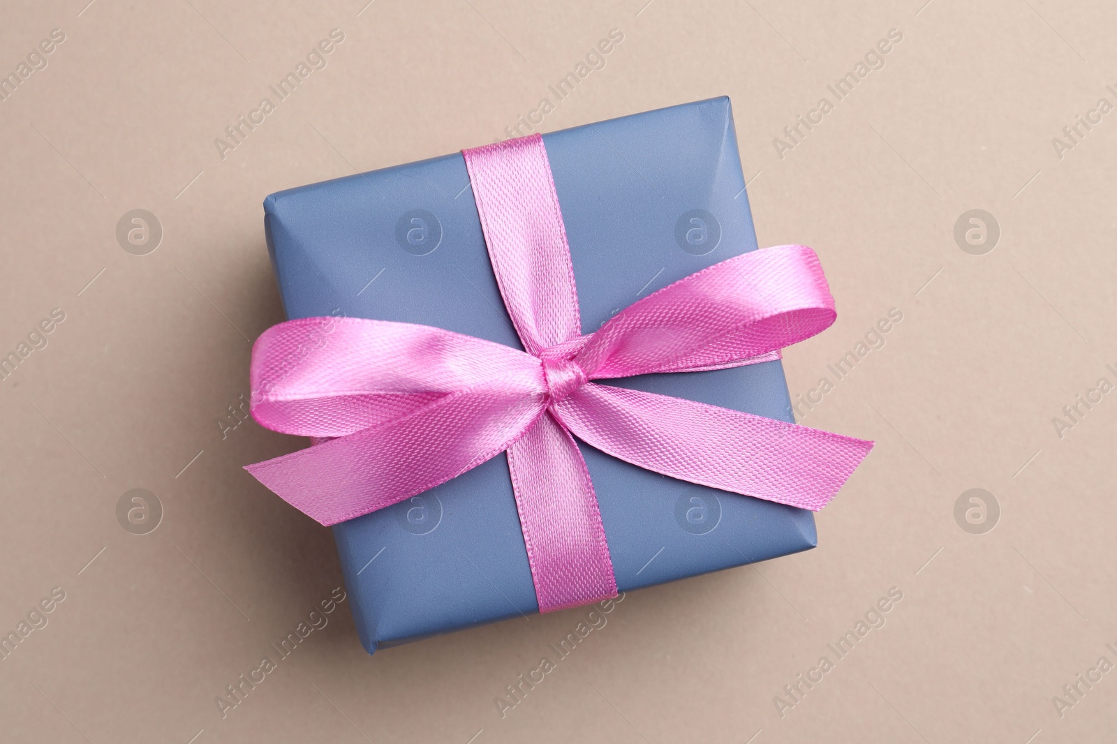 Photo of Gift box with pink bow on beige background, top view