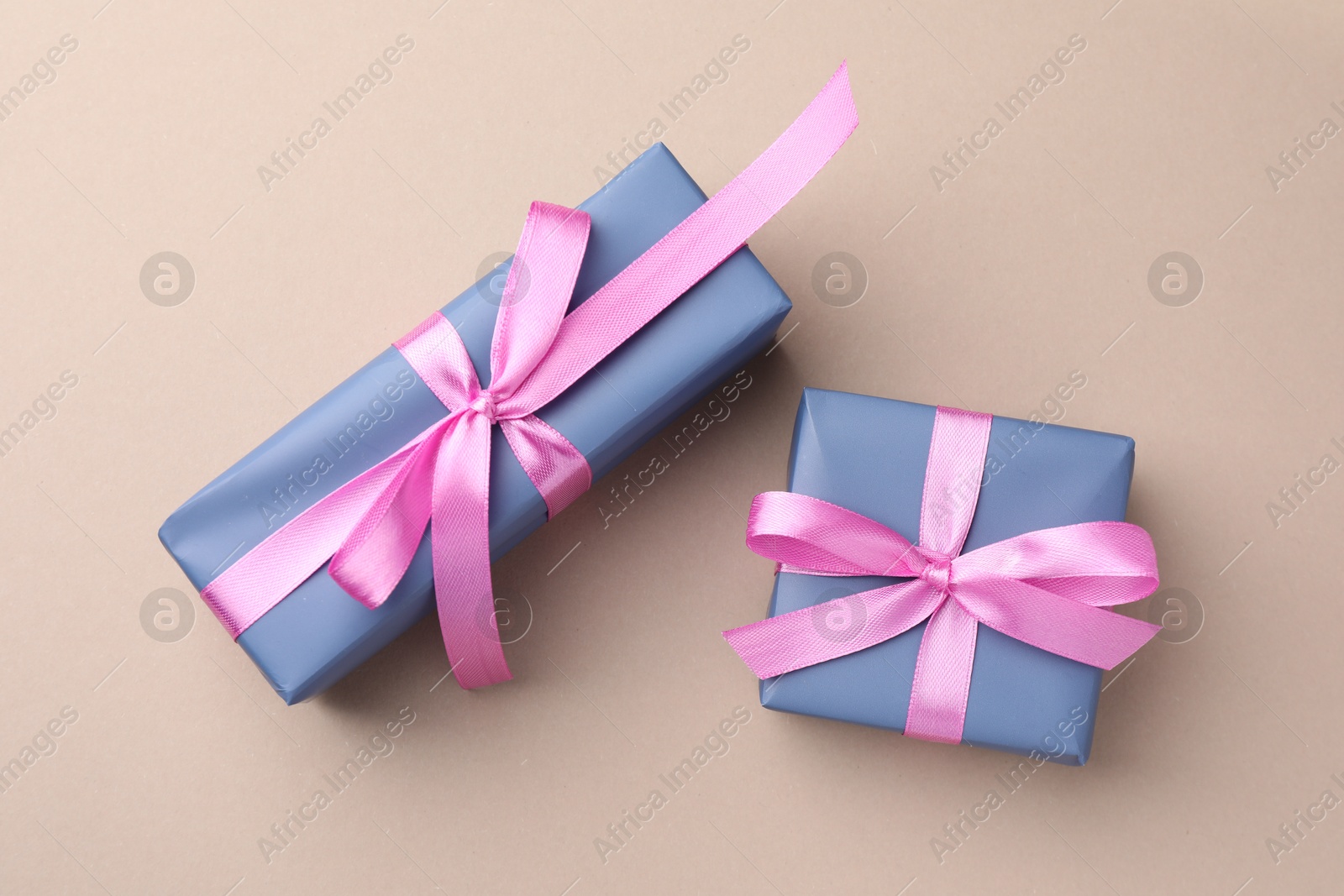 Photo of Gift boxes with pink bows on beige background, top view